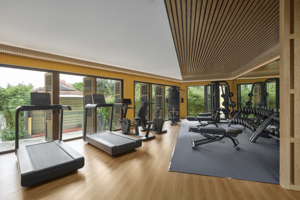 Fitness Centre at Moire Hoi An, Vignette Collection by IHG, featuring modern cardio and strength training equipment in a comfortable setting overlooking lush greenery.