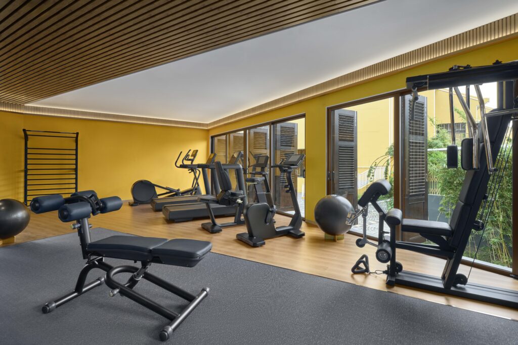Fitness Centre at Moire Hoi An, Vignette Collection by IHG, featuring modern cardio and strength training equipment in a comfortable setting overlooking lush greenery.